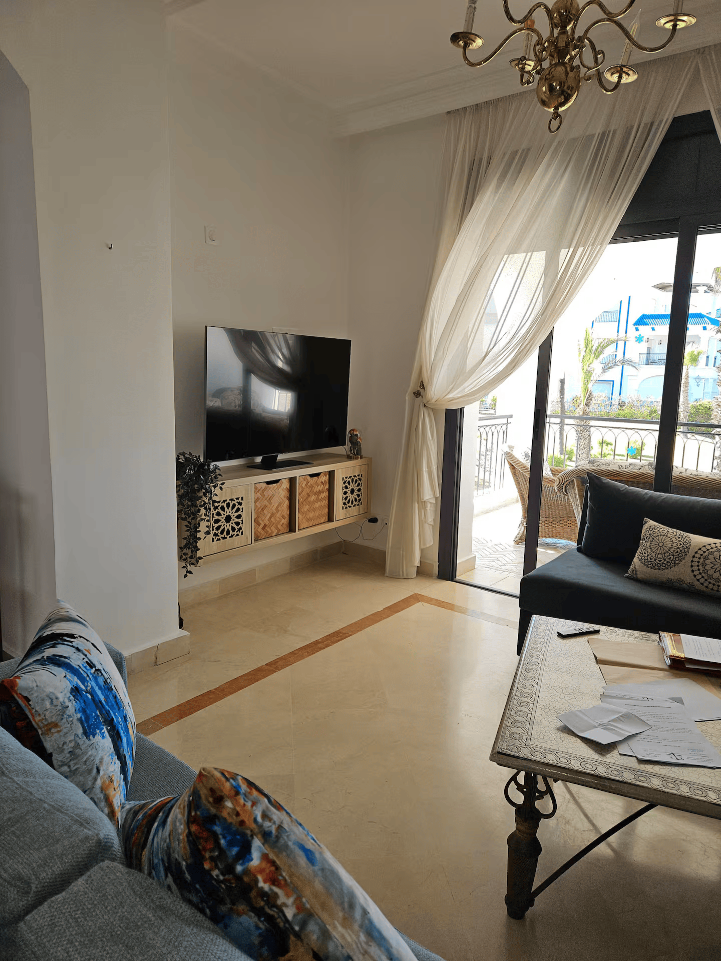 Séjour lumineux ouvert sur le balcon avec vue sur la résidence et les palmiers
